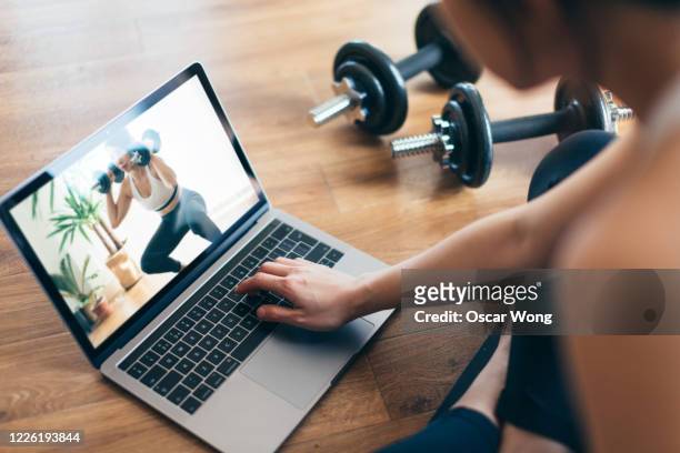 young woman practising weight training workout with a video lesson on laptop. - weight training foto e immagini stock