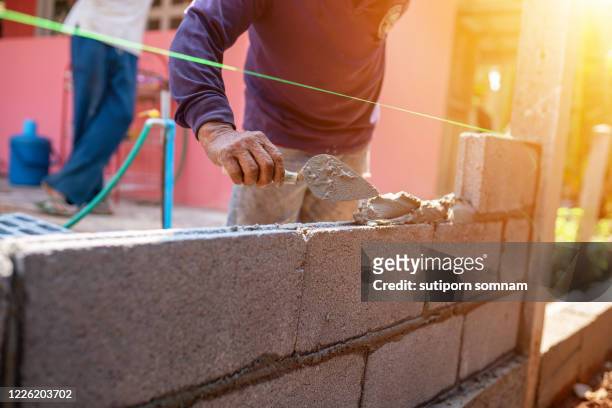 techniques for cement masonry for the construction of building fences - ouvrier maçon photos et images de collection
