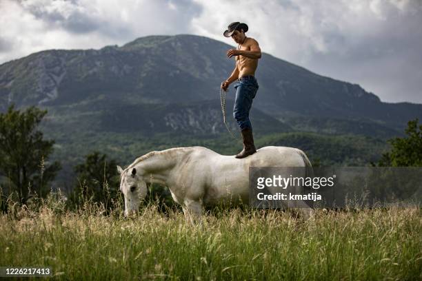 shirtless cowboy standing on horse in rural scene - northern european descent stock pictures, royalty-free photos & images