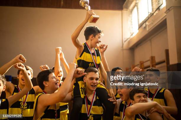 young basketball team celebrating victory and carrying best player on shoulders - sportsperson medal stock pictures, royalty-free photos & images