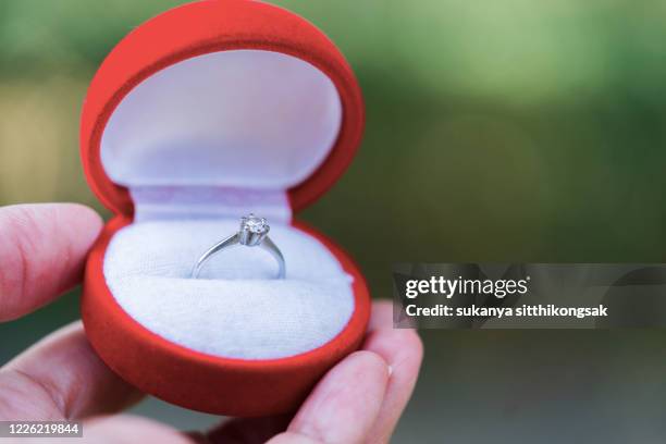 close up of hand holding open red box with engagement silver diamond ring. - man holding engagement ring stock pictures, royalty-free photos & images