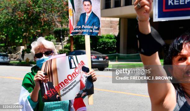 Woman holds a sign as Iranian-Americans protest China's bypassing of US sanctions in doing business with Iran, as well as the handing over of Kish...