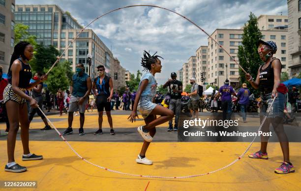 Taylor Blackwell jumps double dutch rope while her mom Danielle Blackwell and sister Jaelynn turn during DC's Chocolate City Experience around Black...