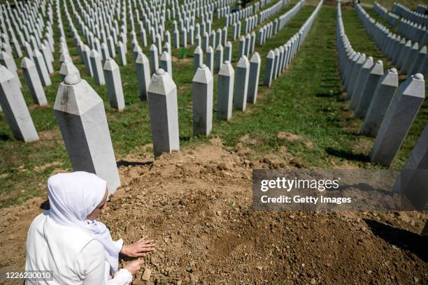 Bosnian Muslim woman touches the freshly dug grave of her father, a victim of Srebrenica genocide on July 11, 2020 at the cemetery in Potocari near...