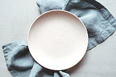 An empty plate and napkin on the gray background.