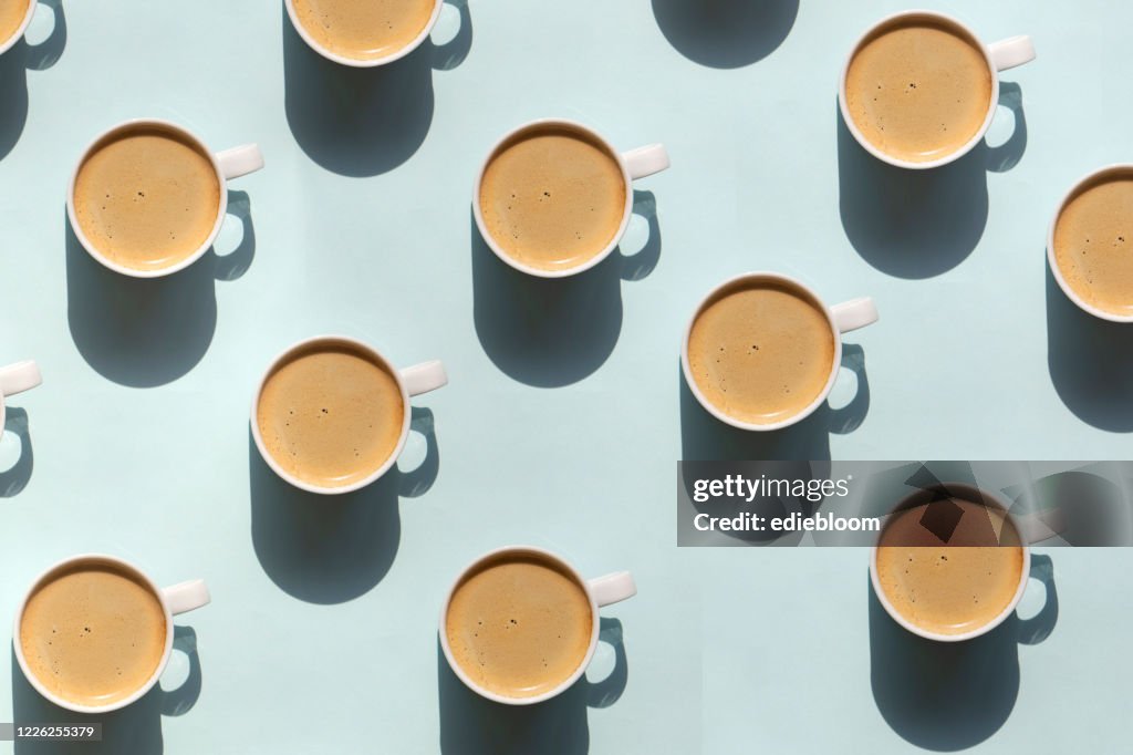 Pattern made of cup of cappuccino on blue background
