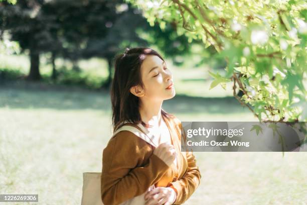 young woman relaxing in nature with eye closed - woman fresh air photos et images de collection