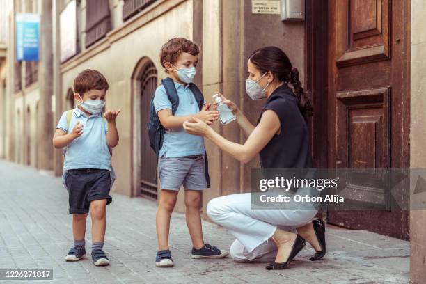 maestro usando desinfectante de manos con niños que regresan a la escuela - pandemia fotografías e imágenes de stock