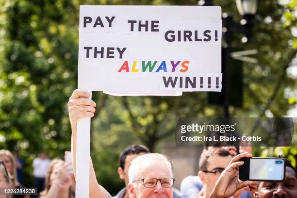 Fan holds up a sign that says "Pay the Girls They Always Win!! in support of the United States Women's National Team fight for equal pay. The Ticker...