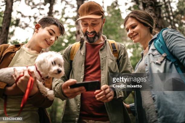 familie mit handy-app auf wandertour - 3 teenagers mobile outdoors stock-fotos und bilder