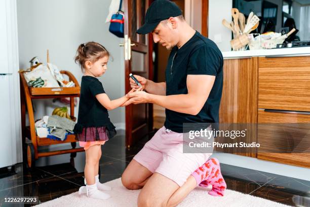 padre está comprobando los niveles de azúcar en la sangre de su hija - insulina fotografías e imágenes de stock