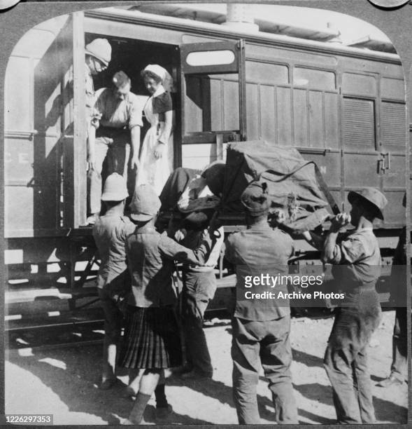 Major Russell and Sister Rose help load wounded soldiers onto a hospital train at Orange River in South Africa during the Second Boer War, 1900.