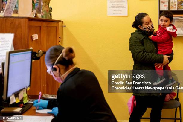 Marlen Valencia of Fremont tries to comfort her 2-year-old daughter Sara as she cries while being prepped to see the doctor at Terra Nova Clinic in...