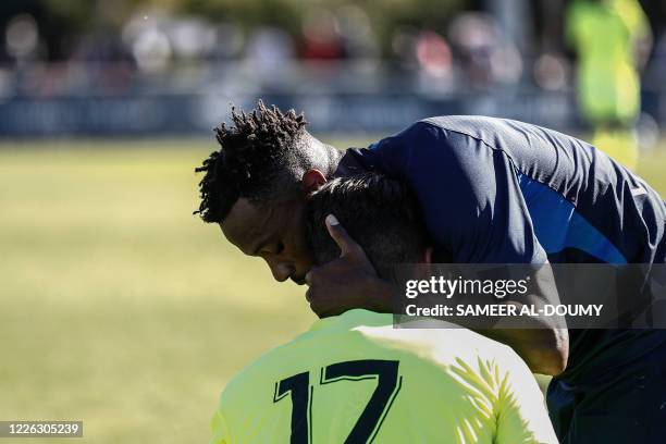 Paris FC's player comforts Caen's French midfielder Anthony Goncalves after he fell during the French L2 friendly football match between Caen and...