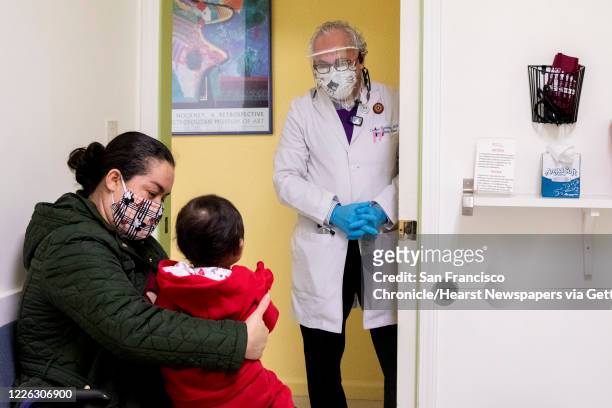 Dr. Carlos Ramirez greets Marlen Valencia of Fremont and her 2-year-old daughter Sara at Terra Nova Clinic in the Fruitvale neighborhood of Oakland,...