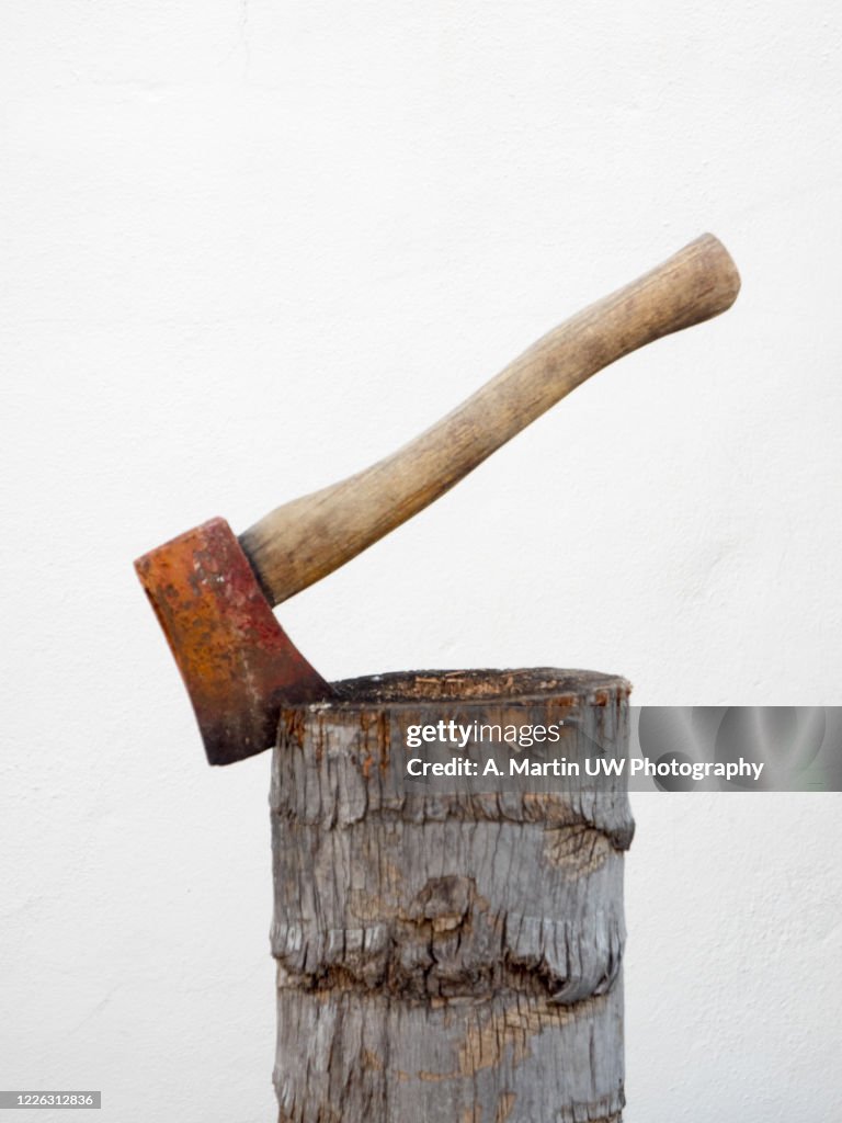 Rusty axe stuck in a wooden log.