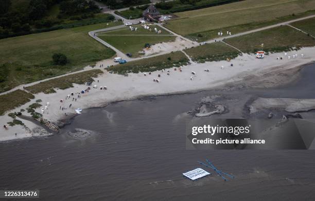 July 2020, Schleswig-Holstein, Fehmarn: Supporters and activists of the protest action "Beltretter" hold a banner with the text "Protect Baltic Sea....