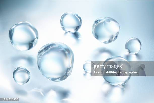 a group of large clear water droplets against blue metallic surface with reflections, close up view in a 45 degree angle - drop stock pictures, royalty-free photos & images