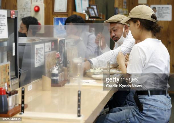 Photo taken on July 12 shows vinyl screens placed at a skewered meat restaurant in Osaka's Shinsekai commercial district to prevent coronavirus...
