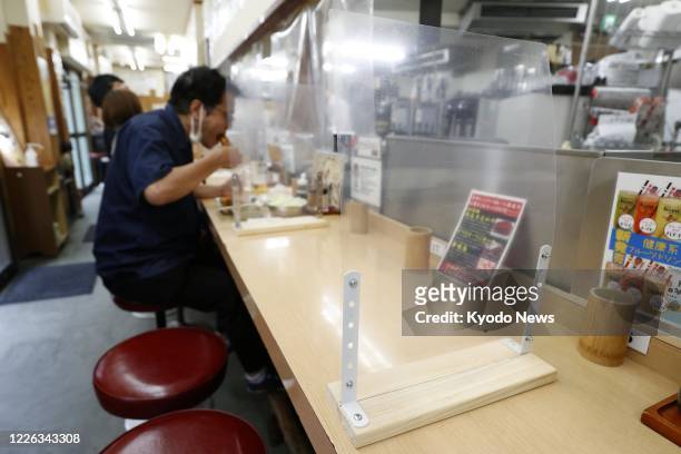 Photo taken on July 12 shows vinyl screens placed at a skewered meat restaurant in Osaka's Shinsekai commercial district to prevent coronavirus...