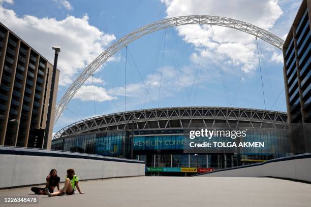 Two women rest in the sunshine in front of Wembley Stadium in London on July 12 the day that Wembley should have hosted the Euro 2020 final, but...