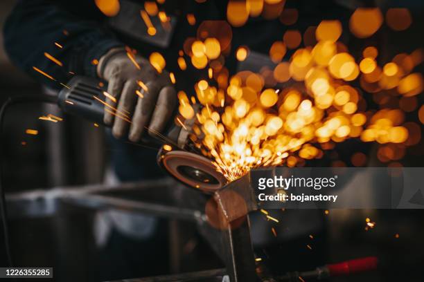 senior mann mit elektroschleifer in der werkstatt - metalwork stock-fotos und bilder