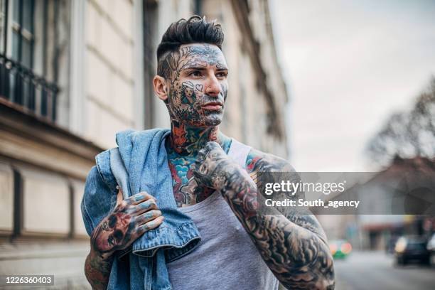 one handsome tattooed man standing on the street in the city - odd one out obscure stock pictures, royalty-free photos & images