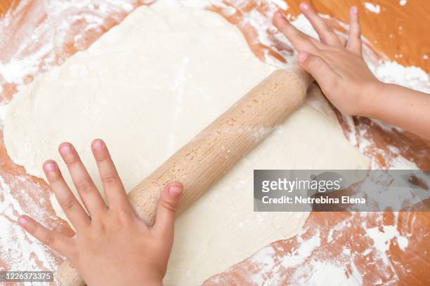 a wooden rolling pin rolls the dough sprinkled with flour. homemade cake. butter dough. space for text. - counter surface level stock pictures, royalty-free photos & images