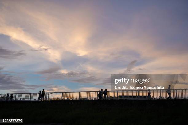 sunset sky and people in silhouette - embankment stock pictures, royalty-free photos & images