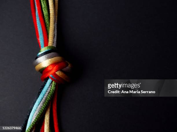 a knot with many twine of different colors on a black background - lint strik stockfoto's en -beelden
