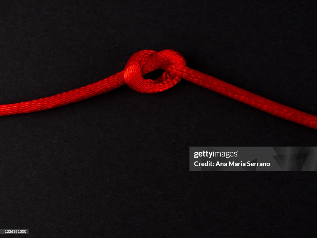 A Knot In A Red Twine On A Black Background High-Res Stock Photo