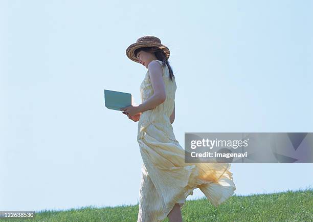 woman reading in field - skirt blowing ストックフォトと画像