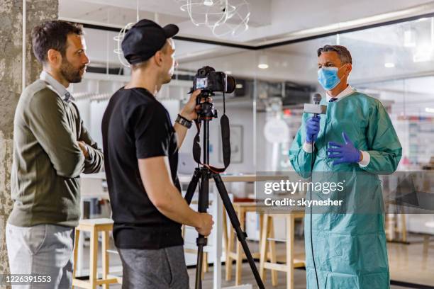 docteur parlant sur un microphone au sujet de l’épidémie courante pendant l’entrevue de tv à l’hôpital. - medical news photos et images de collection