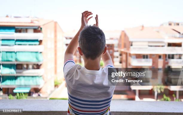 boy clapping and thanking the national health system during covid 19 - applauding balcony stock pictures, royalty-free photos & images