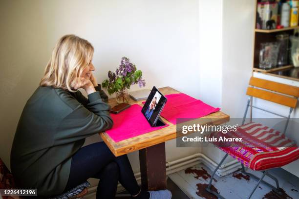 smiling elderly woman enjoying video call in kitchen - covid dating stock pictures, royalty-free photos & images