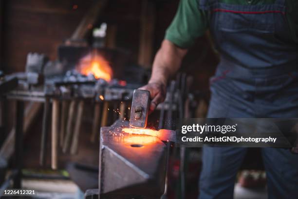 craftsman forges molten metal on an anvil. - forge stock pictures, royalty-free photos & images