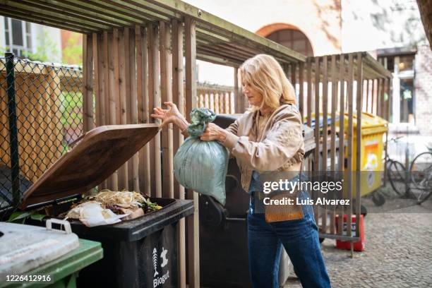 elderly woman throwing garbage in compost bin - lebensmittel müll stock-fotos und bilder