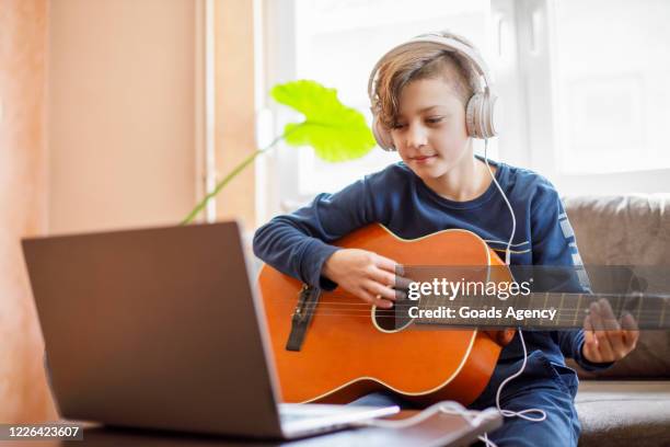 jong geitje met hoofdtelefoons die leren hoe te om gitaar met zijn laptop te spelen op - learn guitar stockfoto's en -beelden