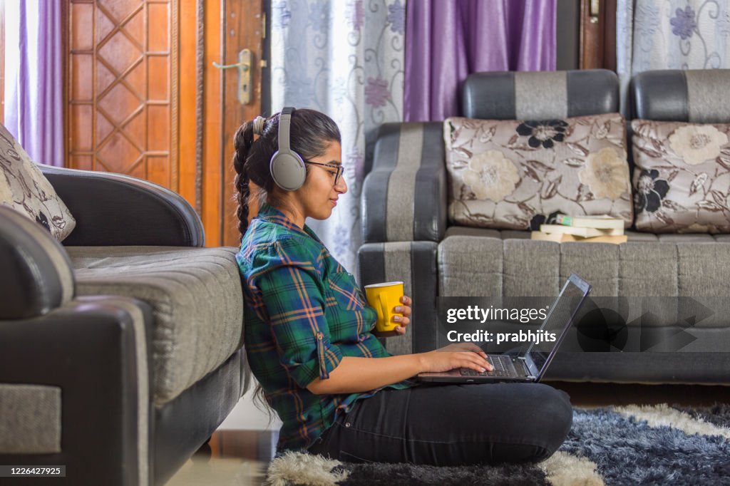 An Indian girl using laptop, sitting on floor