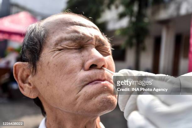 Health worker, wearing protective suit, performs a swab test mass on a old man during in Bandung, West Java, Indonesia, May 10, 2020. Countries...