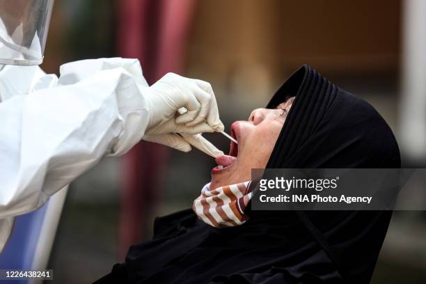 Health worker, wearing protective suit, performs a swab test mass on a woman during in Bandung, West Java, Indonesia, May 10, 2020. Countries around...