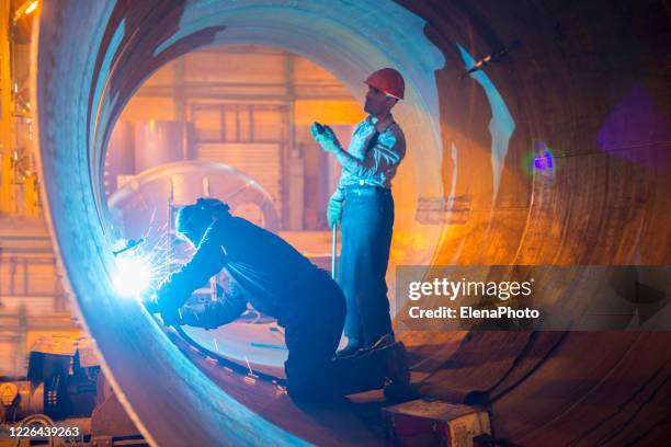 two welders work in a pipe for an oil pipeline. - oil pipeline stock pictures, royalty-free photos & images