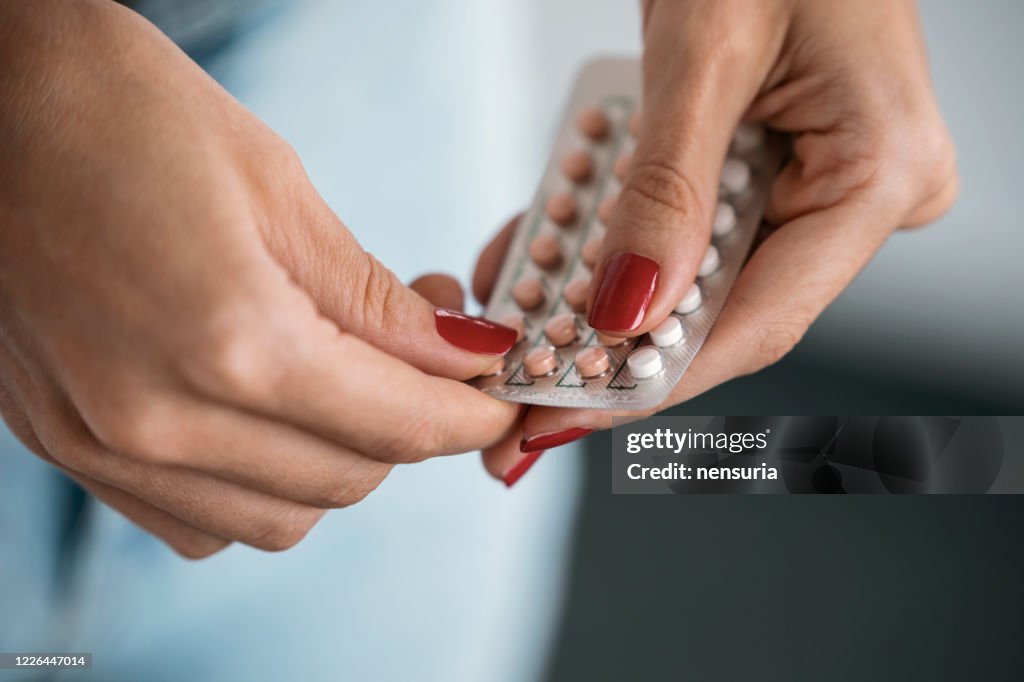 Mulher segurando uma pílula anticoncepcional. Conceito de métodos de contracepção.