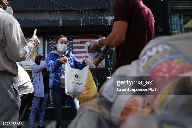 People receive food after waiting on line for hours outside of a Brooklyn mosque and cultural center on May 22 , 2020 in New York City. The center...