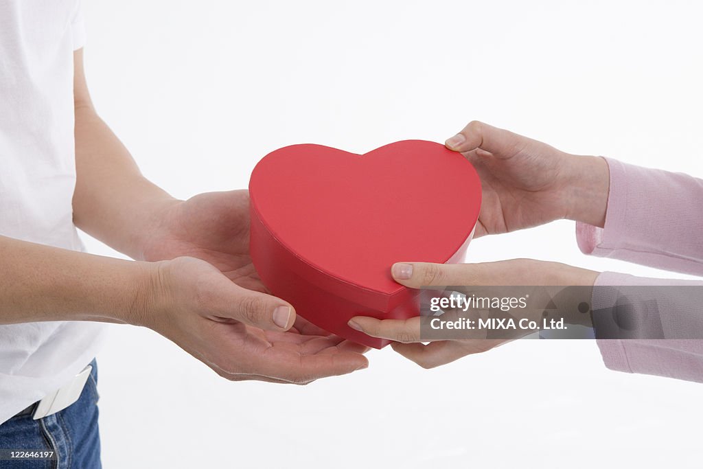 Woman giving man heart-shaped box