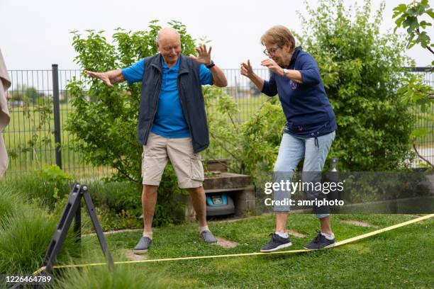 coppia senior divertirsi su slackline in giardino - slackline foto e immagini stock