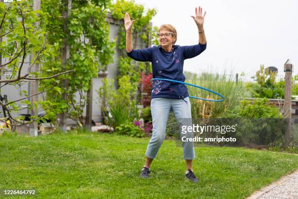 幸せなシニア女性フラフープ庭で喜んで - フープ ストックフォトと画像