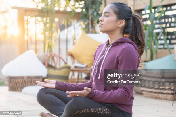 zuidoost-aziatisch wijfje dat yoga op haar dek tijdens zonsondergang doet - adem inhouden stockfoto's en -beelden