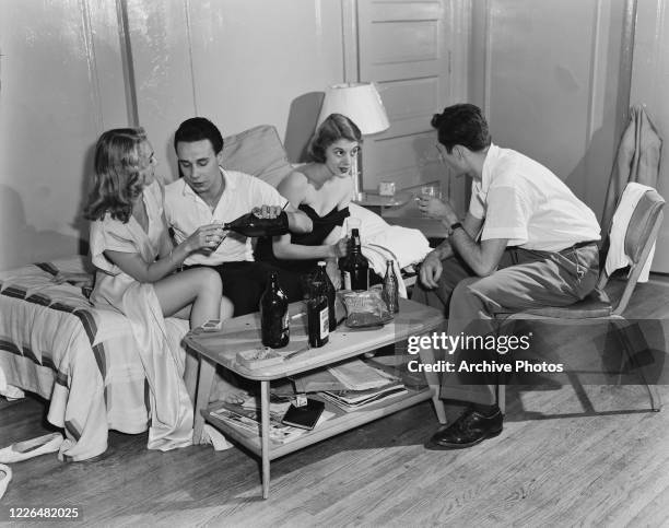 Young men and women smoking marijuana joints and drinking Four Roses Kentucky bourbon at a party, USA, 1950.