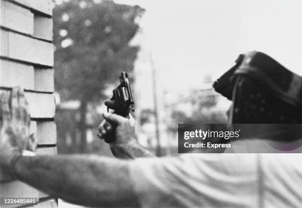 Newark police officer shelters from a sniper during the race riots in Newark, New Jersey, 16th July 1967. The riots were sparked by the beating of...